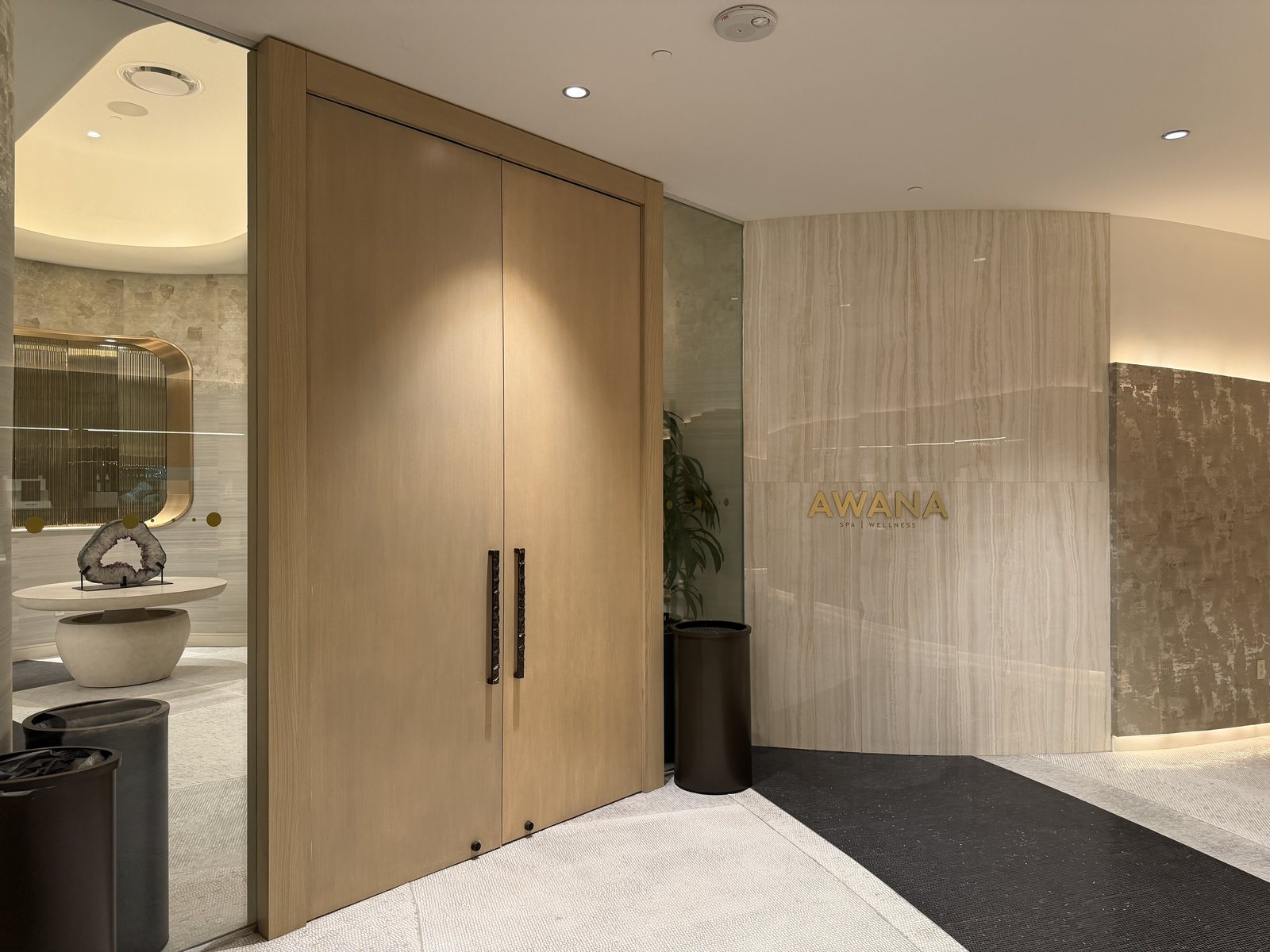 The entrance to Awana Spa and Wellness at Resorts World Las Vegas, with its gold wordmark on a stone wall beside the reception doors