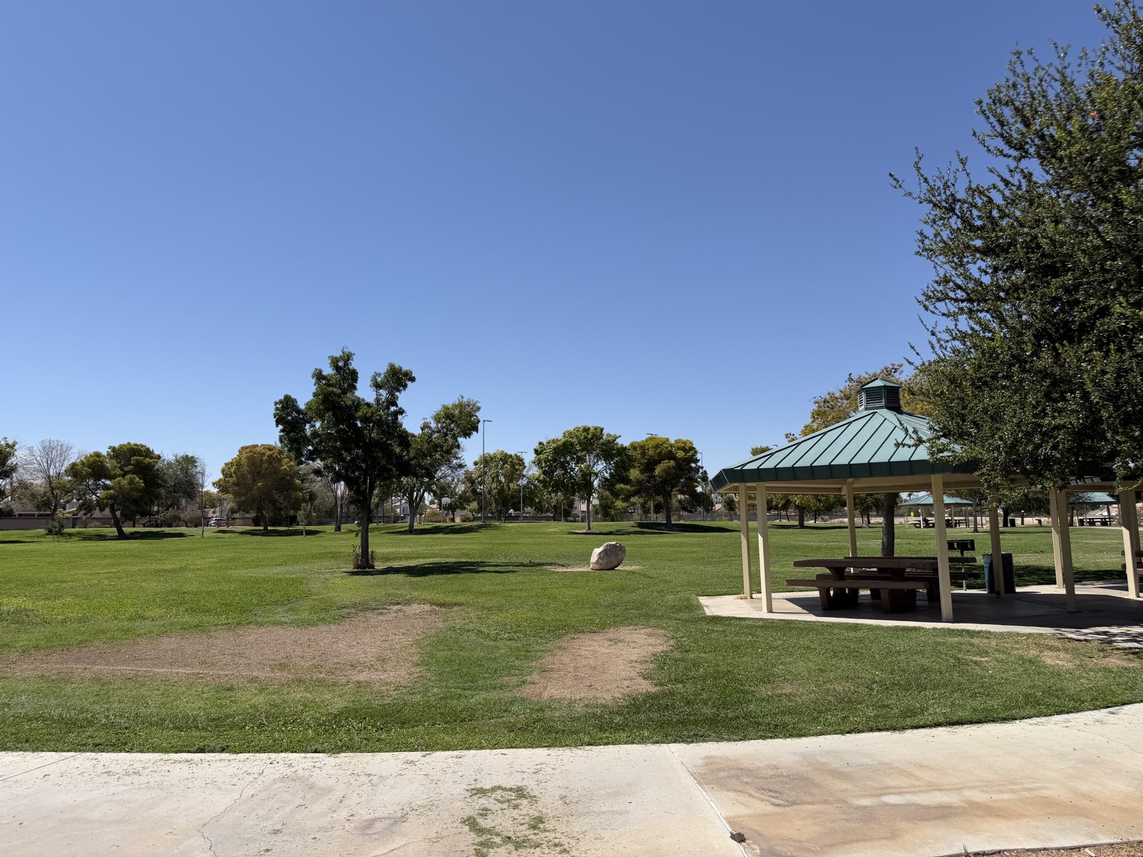 A covered picnic ramada with tables beside open turf at Desert Bloom Park in Southeast Las Vegas