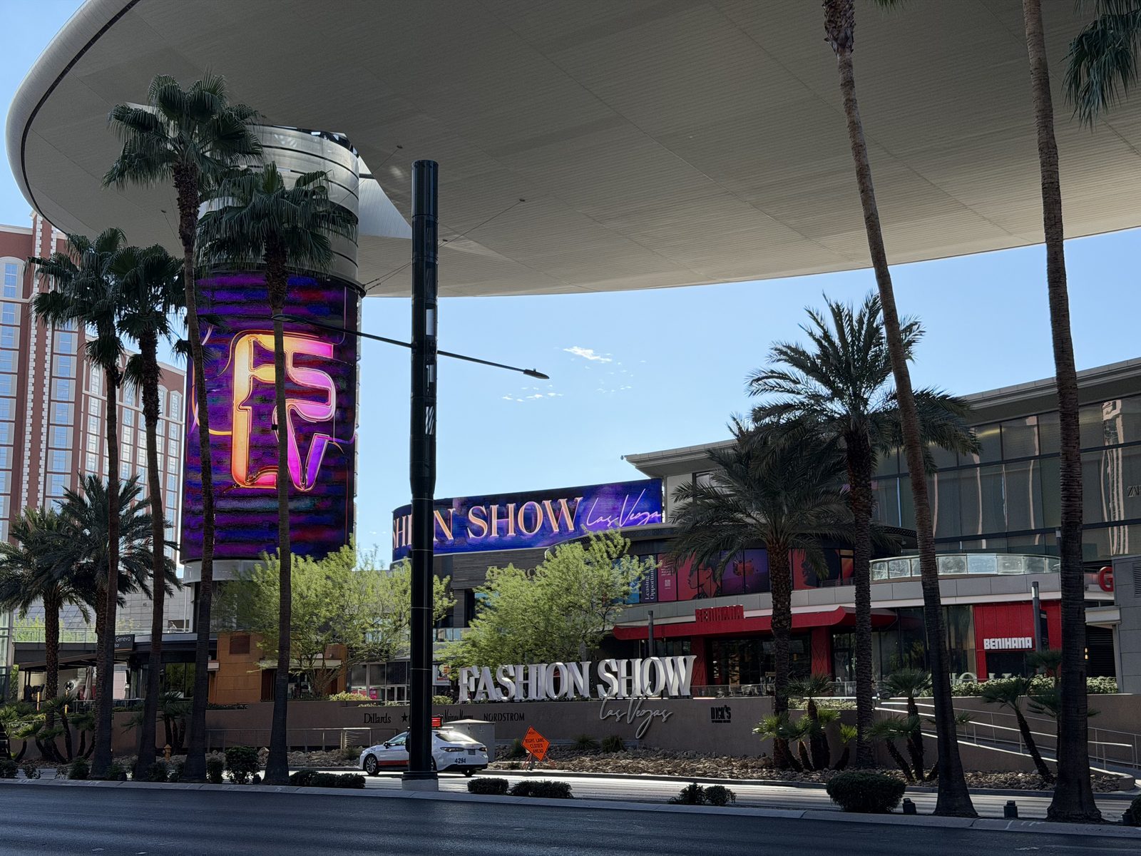 The sweeping steel canopy over Fashion Show Mall on the Las Vegas Strip with palm trees and Treasure Island behind