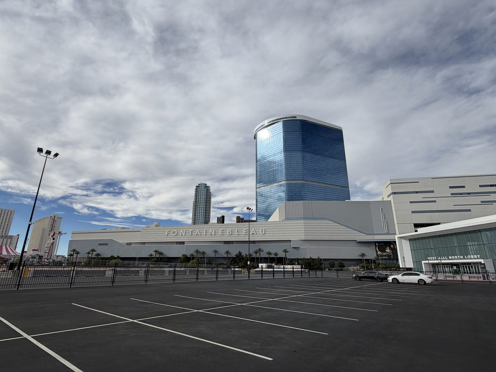 The blue glass Fontainebleau tower above its low-rise podium, with the Las Vegas Convention Center West Hall North Lobby entrance at the right of the same frame