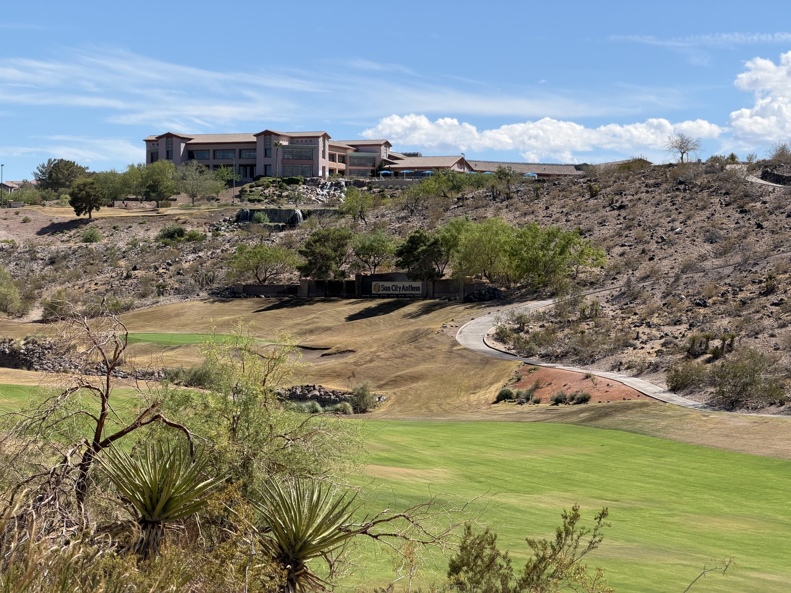 A clubhouse on the ridge above a green golf fairway cut through desert canyon in Anthem, Henderson