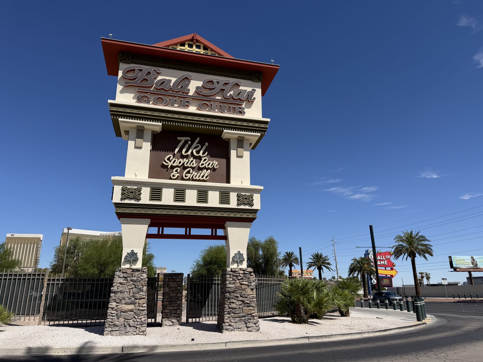 The tall tiki-style tower sign at the Bali Hai Golf Club entrance, with the Mandalay Bay and Delano towers visible along the Strip behind it