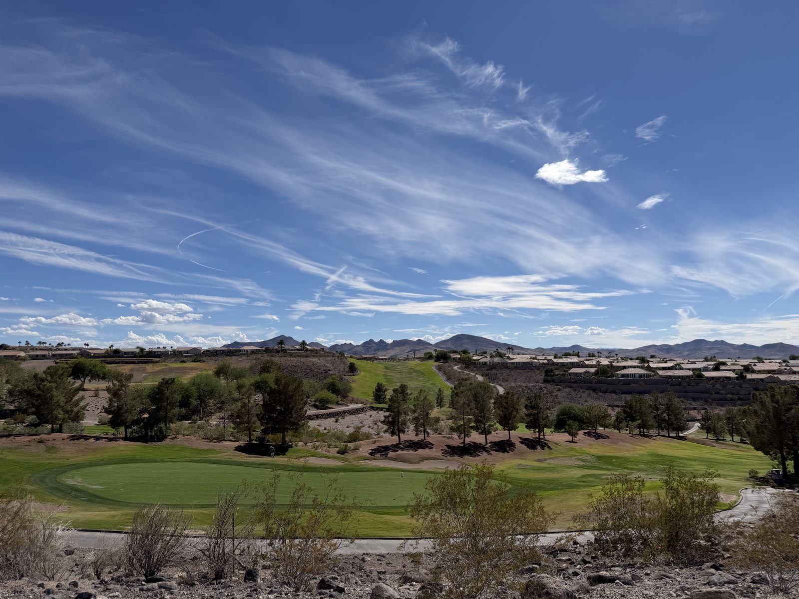A green fairway at The Revere Golf Club in Anthem running into desert canyon with mountains on the horizon
