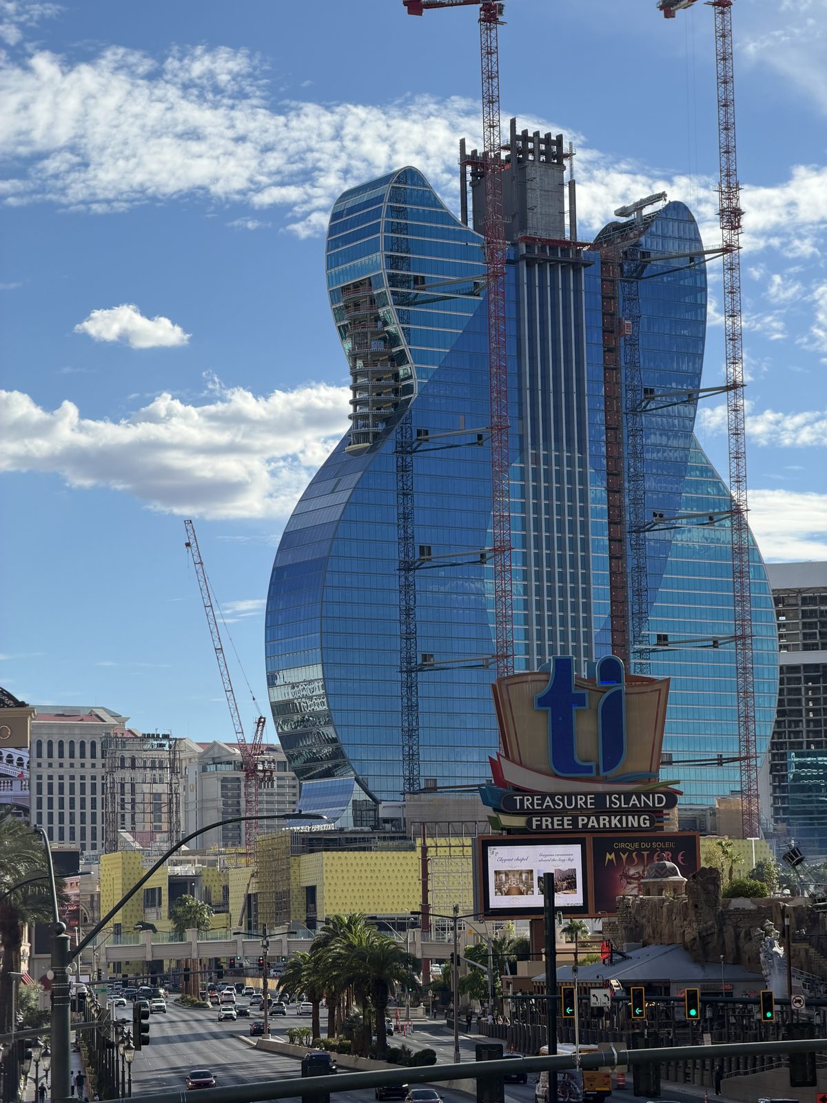 The guitar-shaped Hard Rock hotel tower under construction on the Las Vegas Strip, cranes still standing against a blue sky