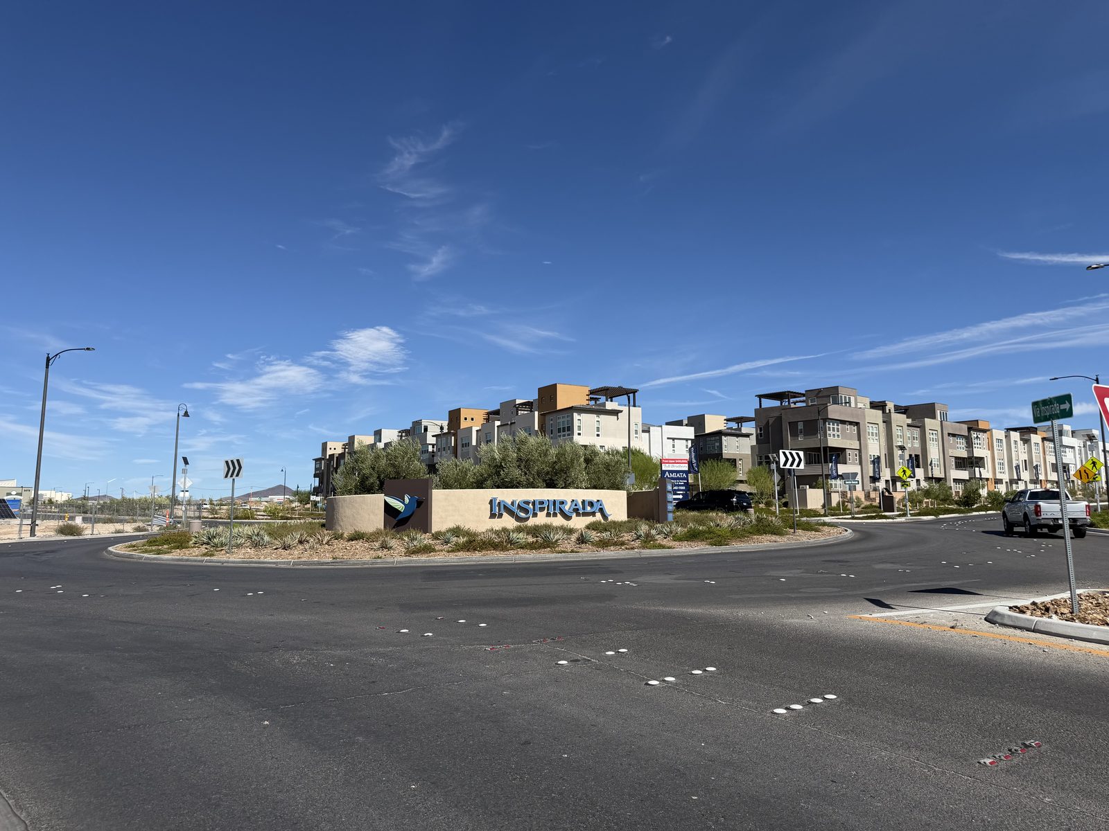 The Inspirada monument sign at a roundabout in Henderson with contemporary multi-storey homes behind it