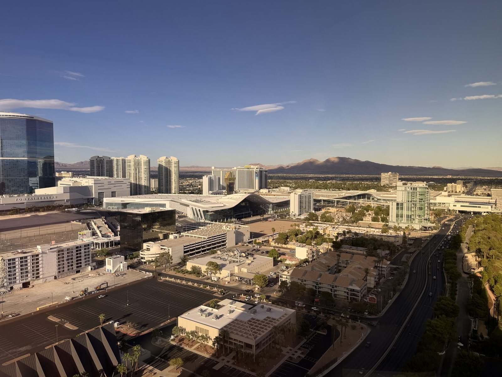 Elevated view south over the Las Vegas Convention Center halls toward the Strip with mountains on the horizon