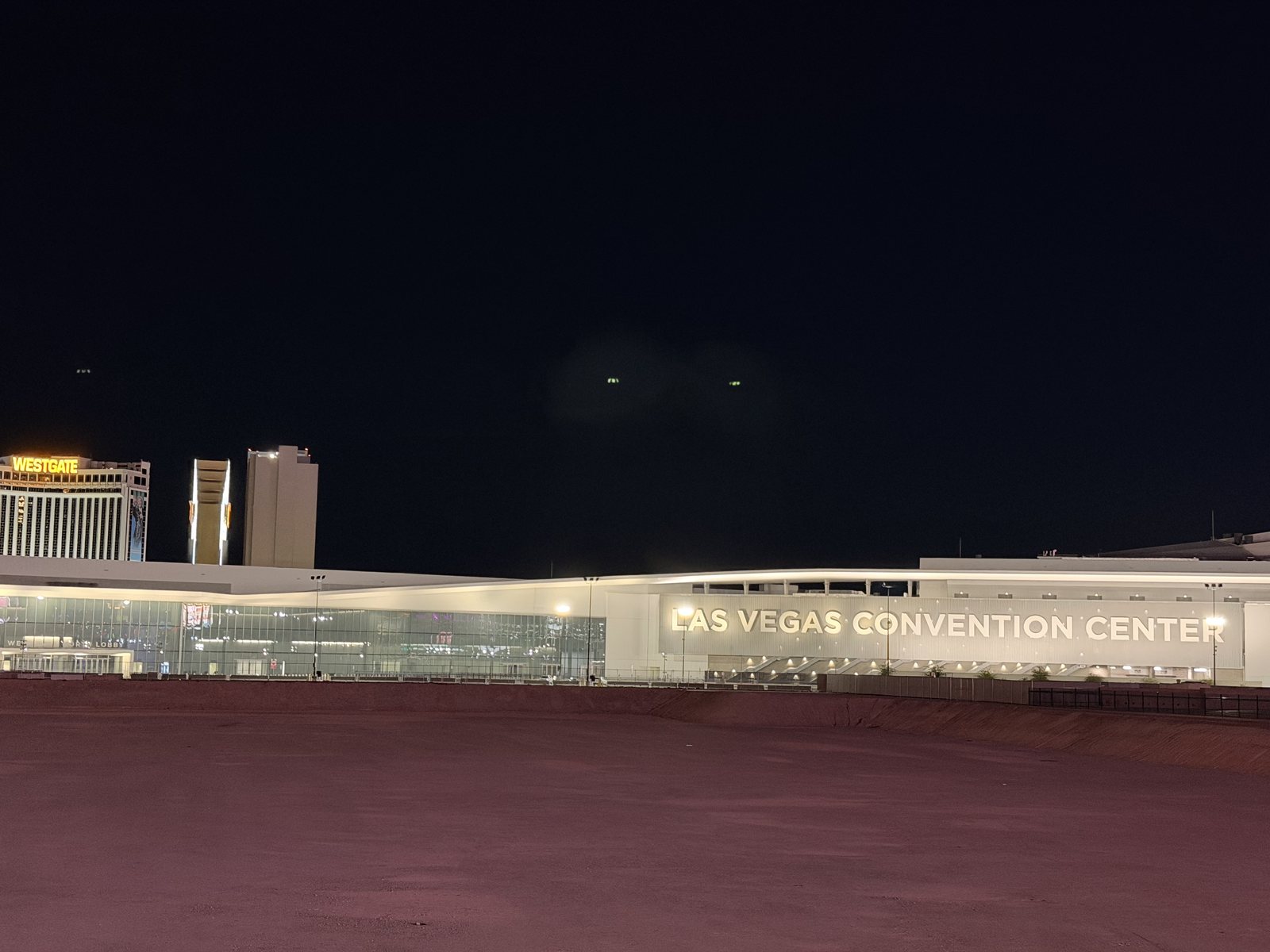Night view across the vacant Riviera parcel toward the lit Las Vegas Convention Center with the Westgate sign glowing behind it