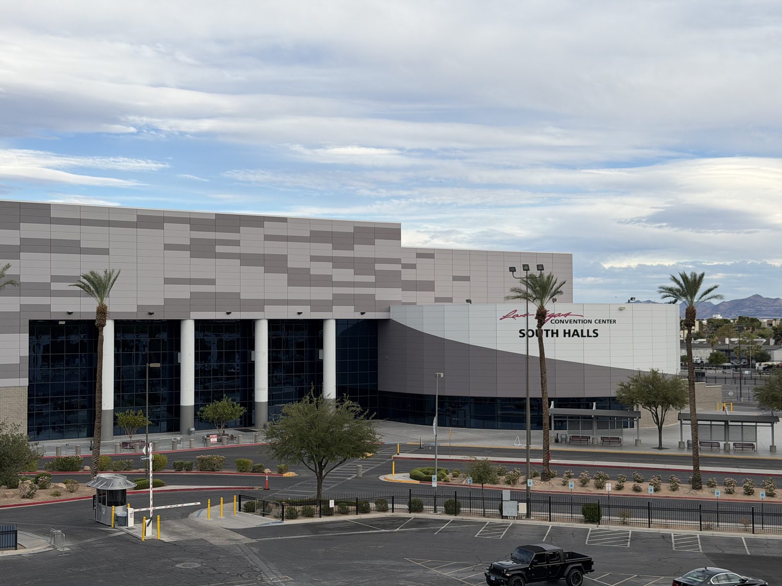 The Las Vegas Convention Center South Halls building with its grey panelled facade, palm trees and the mountains behind