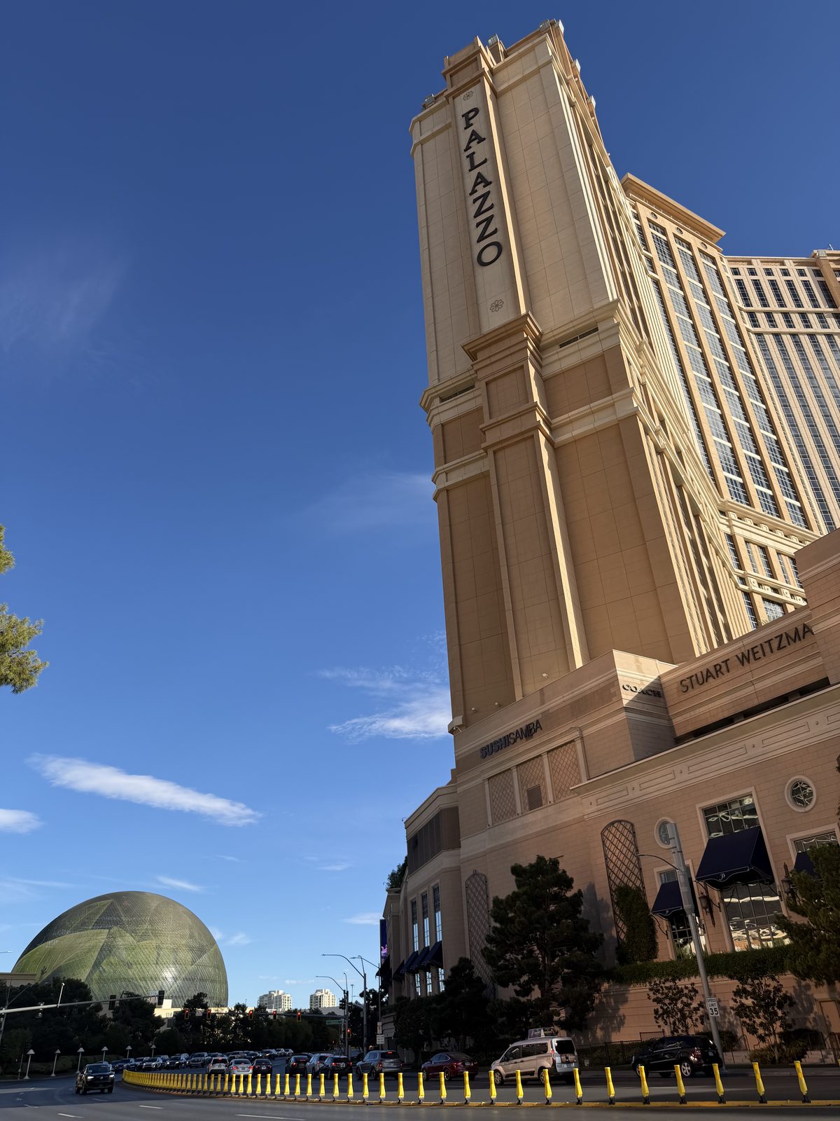 The Palazzo tower rising above the trees on the Las Vegas Strip with the Sphere visible beyond it