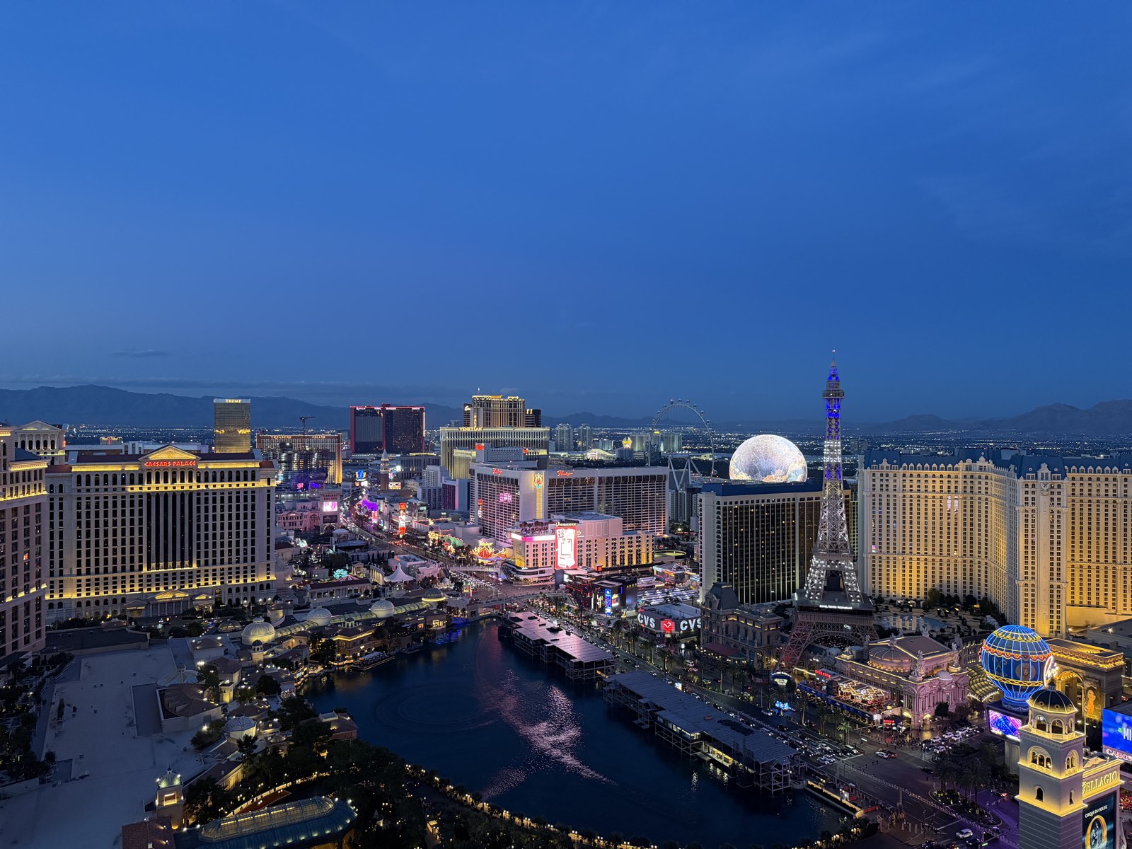 Aerial view of the Las Vegas Strip at blue hour, with the Sphere, the Eiffel Tower at Paris Las Vegas, and the Bellagio fountains lit below