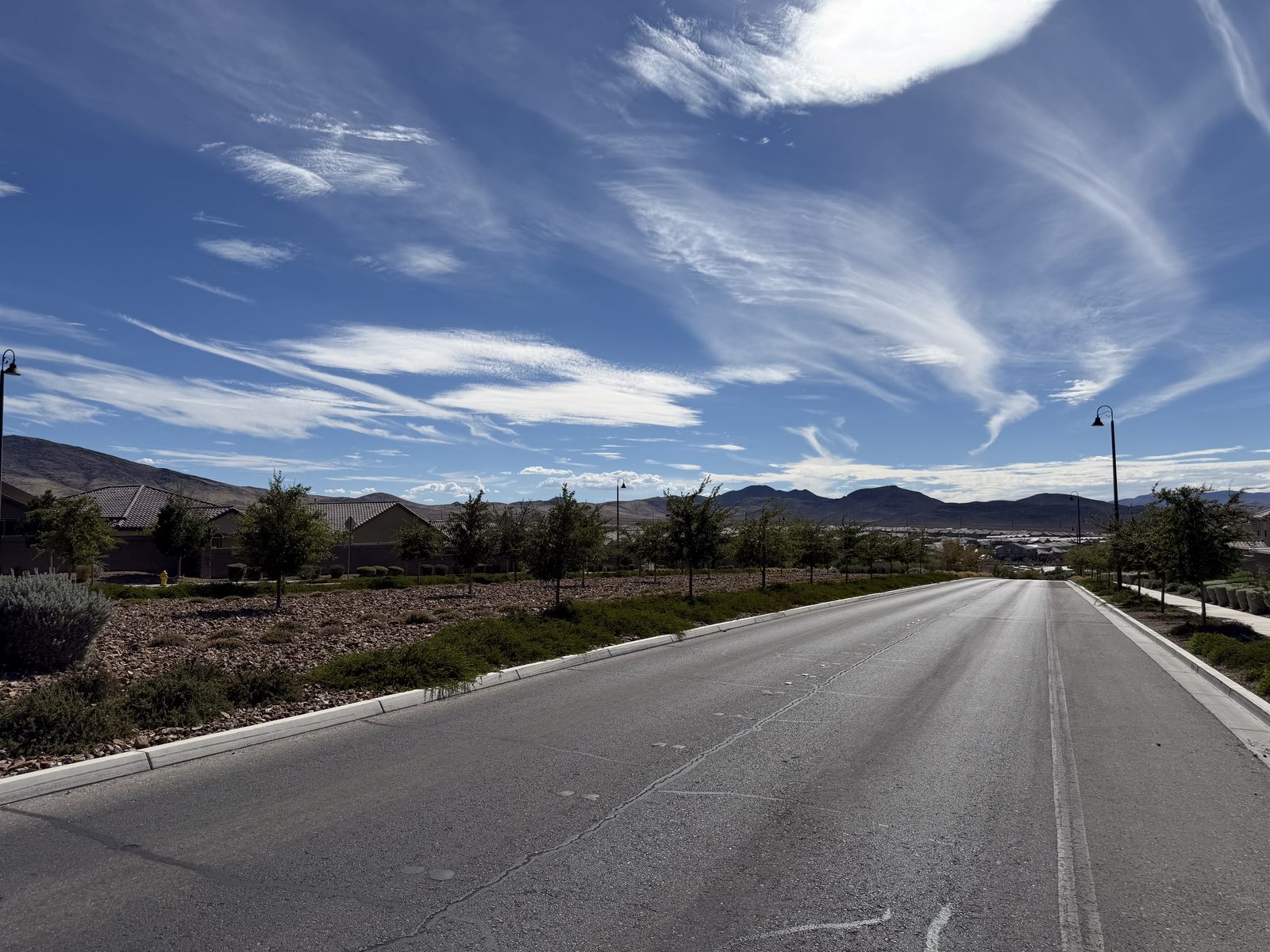 Single-storey tile-roofed homes across an open parcel in the Las Vegas valley under a wide desert sky, mountains on the horizon