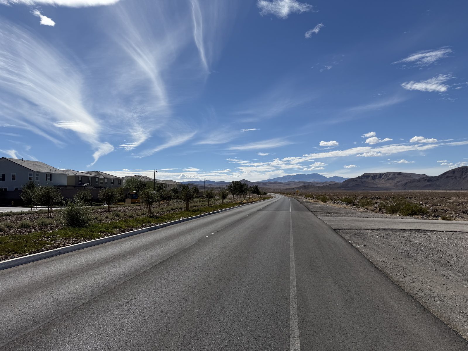 A road at the edge of a new master-planned community in the Las Vegas valley, homes along one side and open desert and mountains along the other