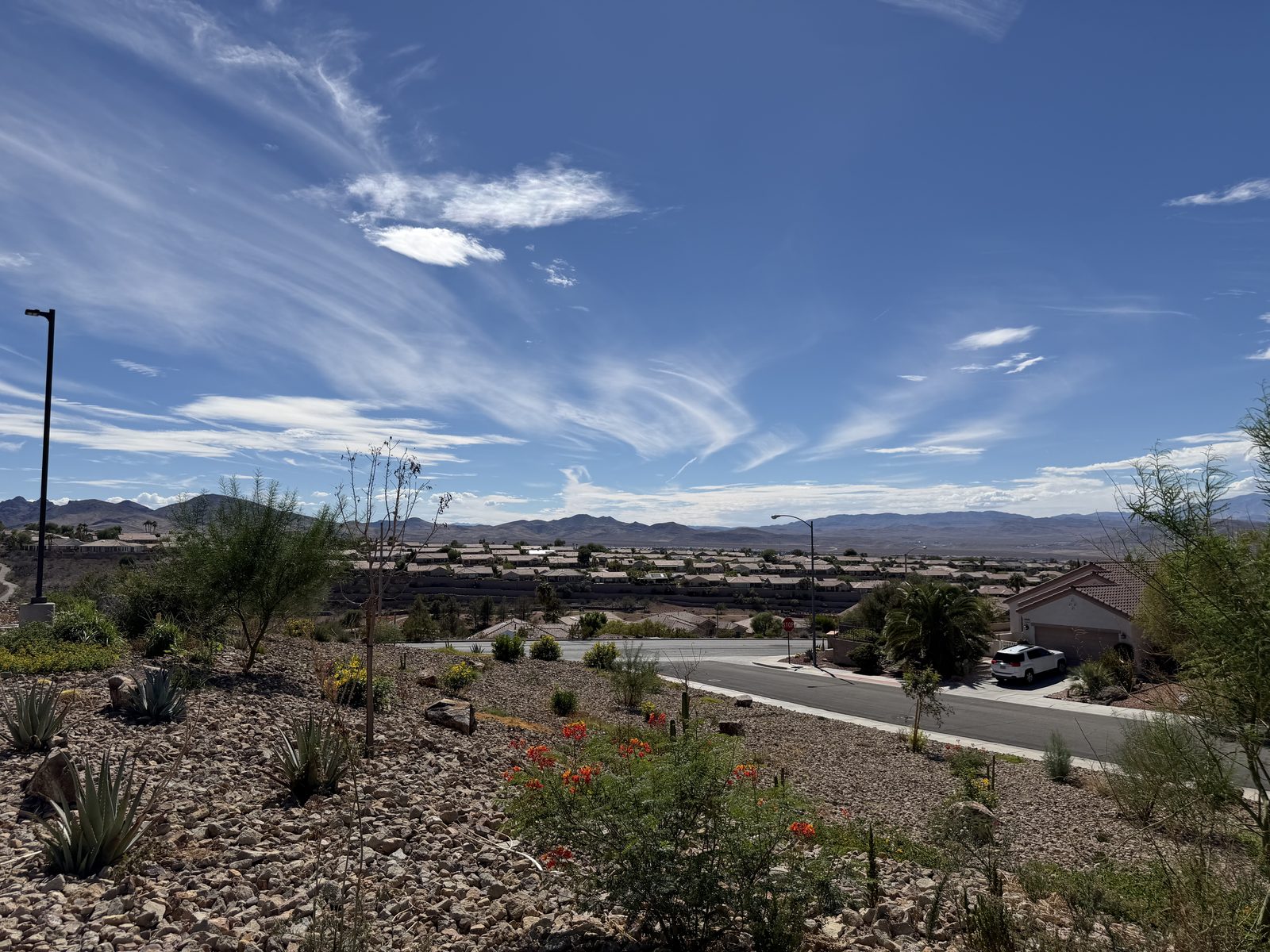 A hillside street in Henderson looking out over rooftops across the southern Las Vegas valley to the mountains beyond