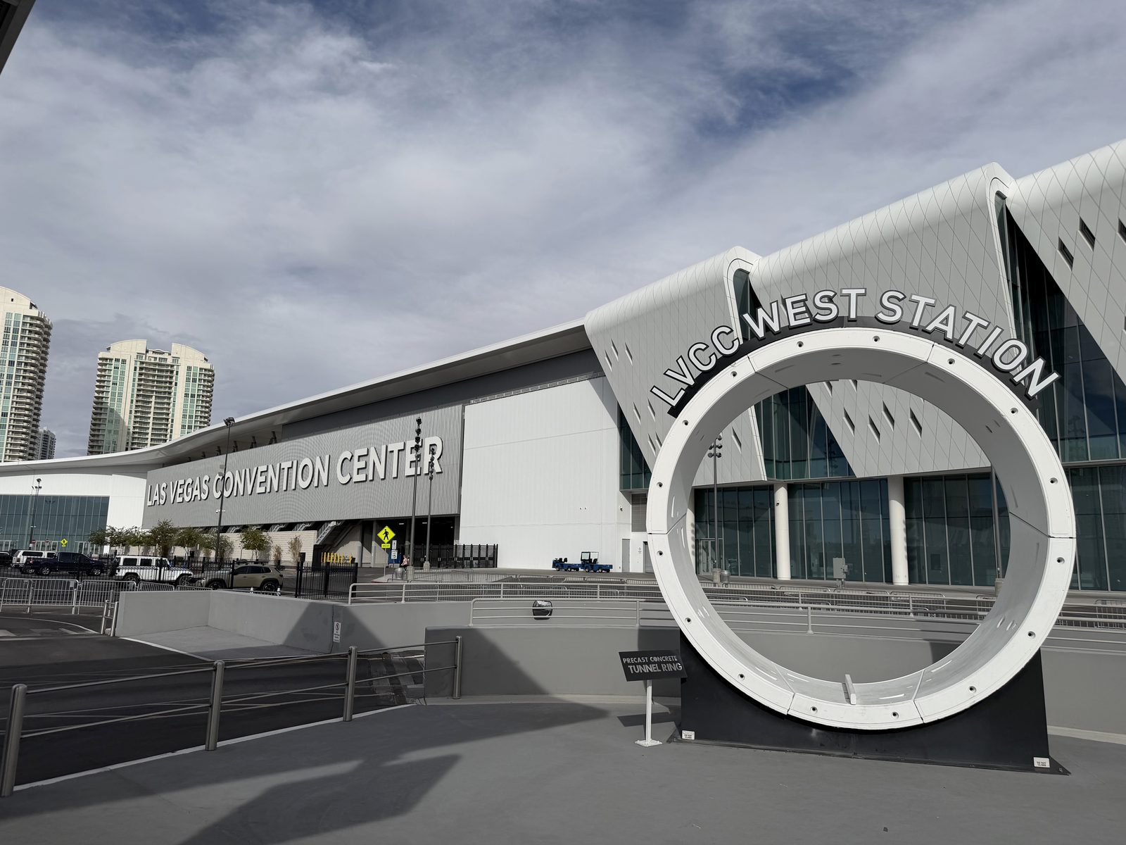 The LVCC West Station entrance of the Vegas Loop, with a white tunnel boring ring displayed beside the ramp down to the tunnels and the convention center signage alongside