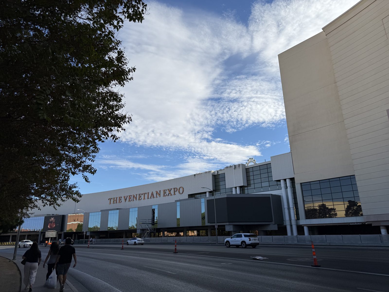 The long facade of The Venetian Expo on Sands Avenue, with the Venetian tower rising behind it and pedestrians walking along the sidewalk