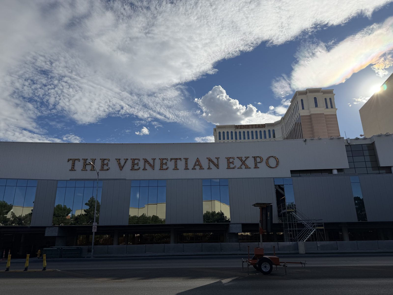 The Venetian Expo lettering along the hall facade with the Venetian hotel tower and afternoon clouds behind