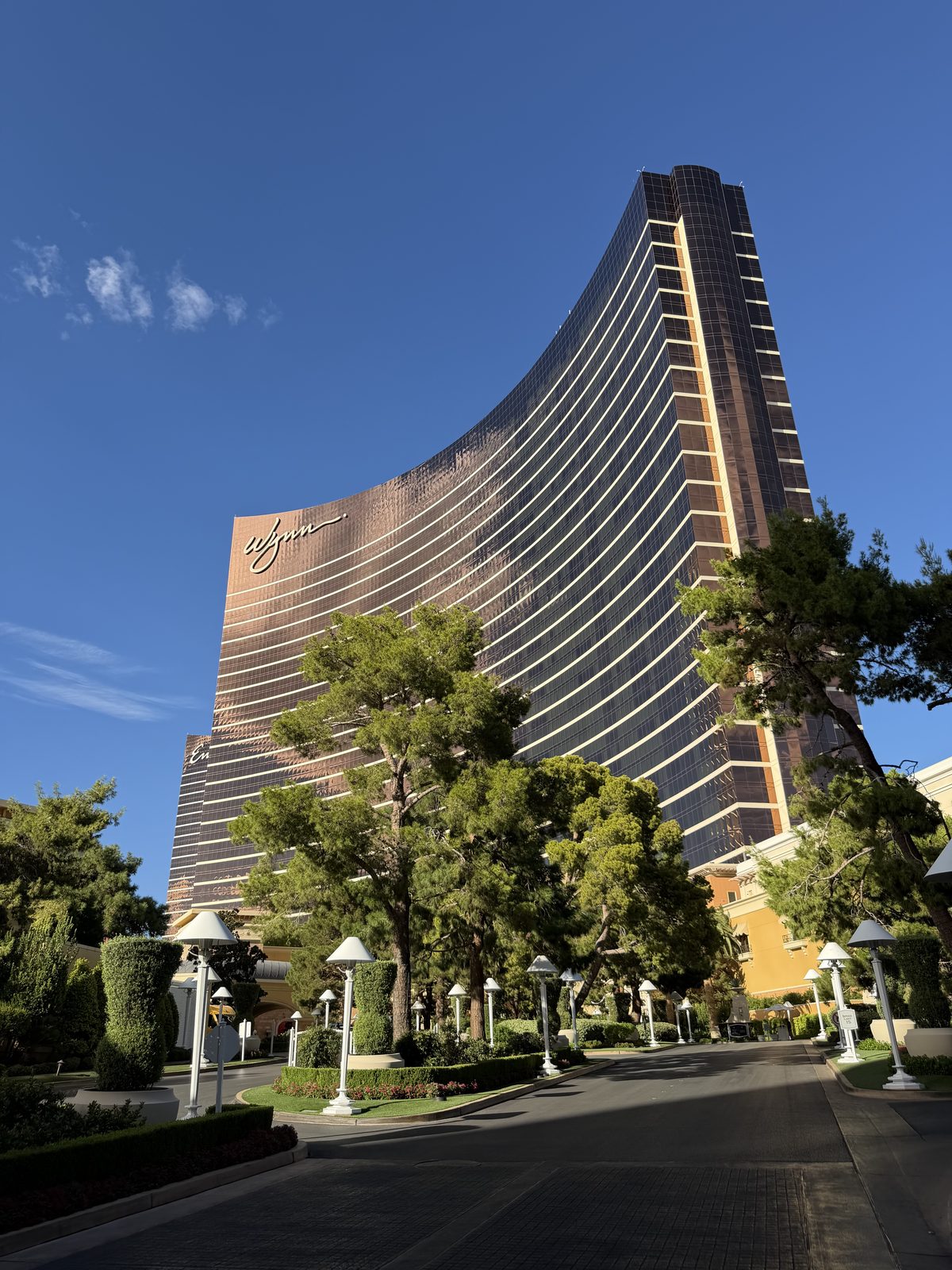 The curved bronze Wynn tower on the Las Vegas Strip seen from its garden entrance drive, catching afternoon light